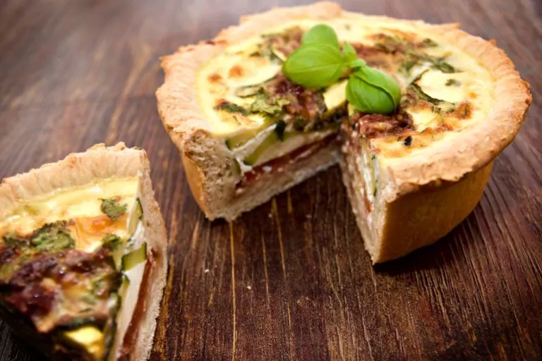 A delicious deep layered Mediterranean quiche with basil garnish